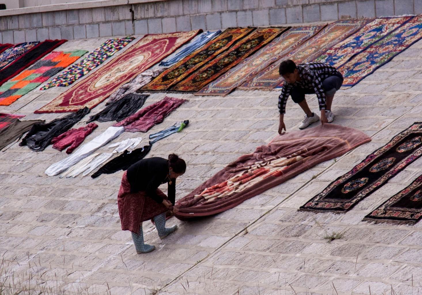 Drying washed blankets on the river bank.