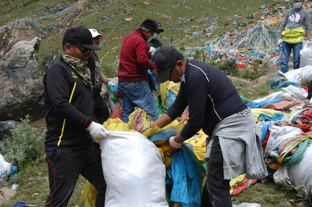 Volunteers put garbage and old prayr flags into gunny bags.