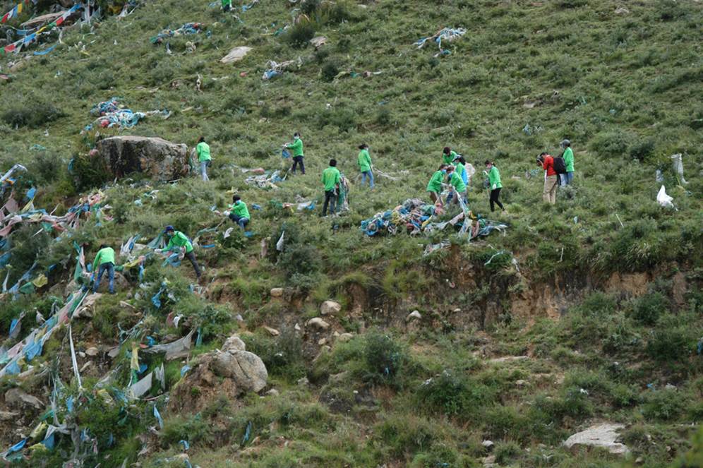 They begin to climb and gather old prayer flag,and pick up garbage.