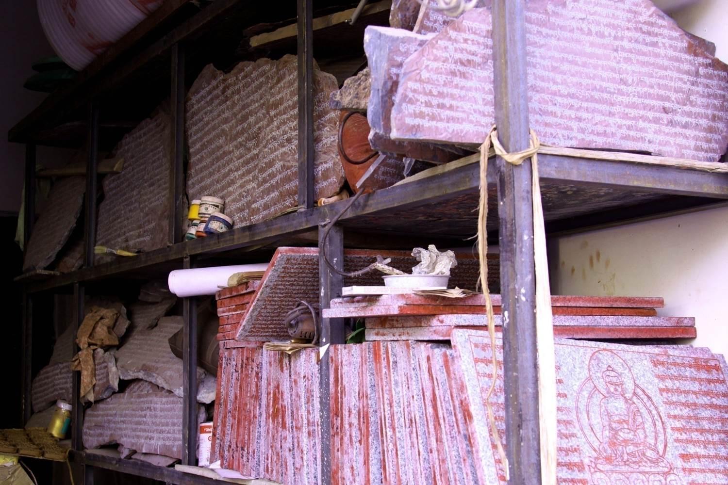 A shelf of his store is filled with mani stones made by him and his apprentices.These are pieces of stones carved with Tibetan sutras or Buddha figures.