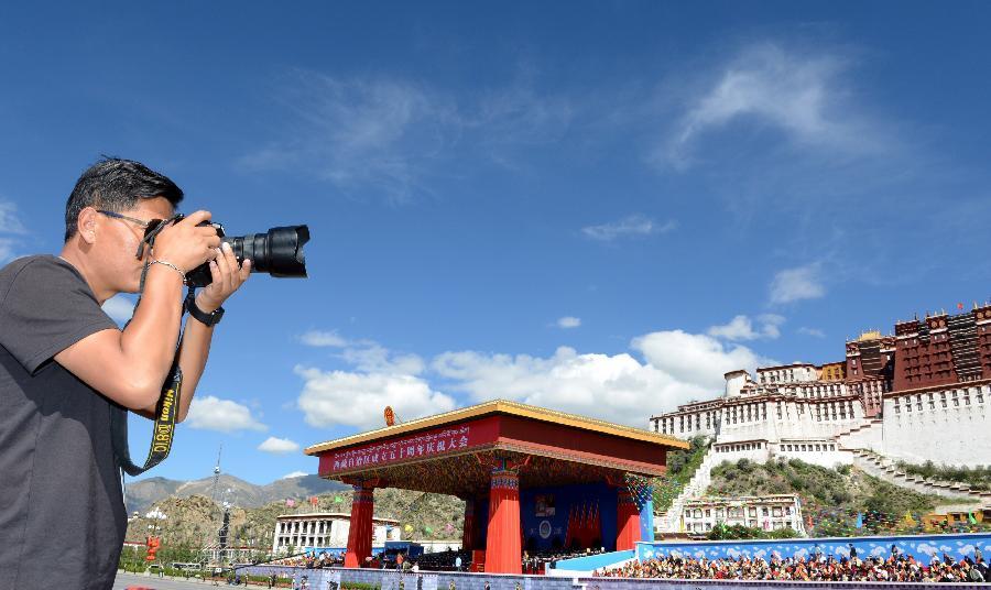 On September 8, 2015, journalist from China News Agency is taking a photo on the ceremony of the 50th anniversary of the founding of the Tibet Autonomous Region. Although Tibet is high-cold and oxygen deficit, the journalists who record Tibet work in areas under the most harsh conditions and they tell the world what is happening on the plateau to let more people know about Tibet and the lives of Tibetan people.[Photo/Jue Guo]