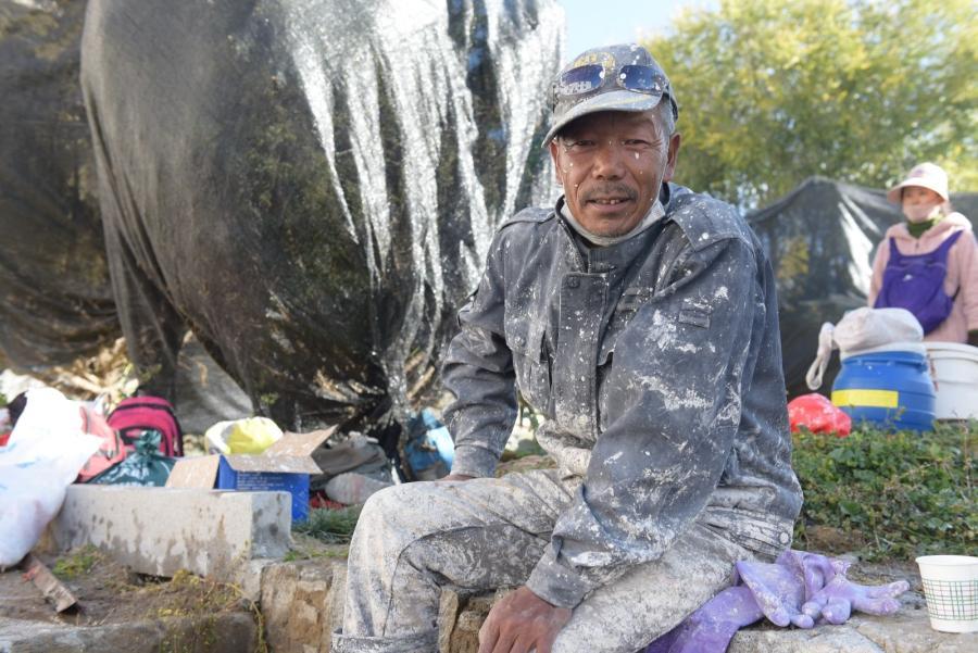 Dradul, a 51-year-old man, drinks some water and smokes at rest. He says that he never miss a day during the painting every year.