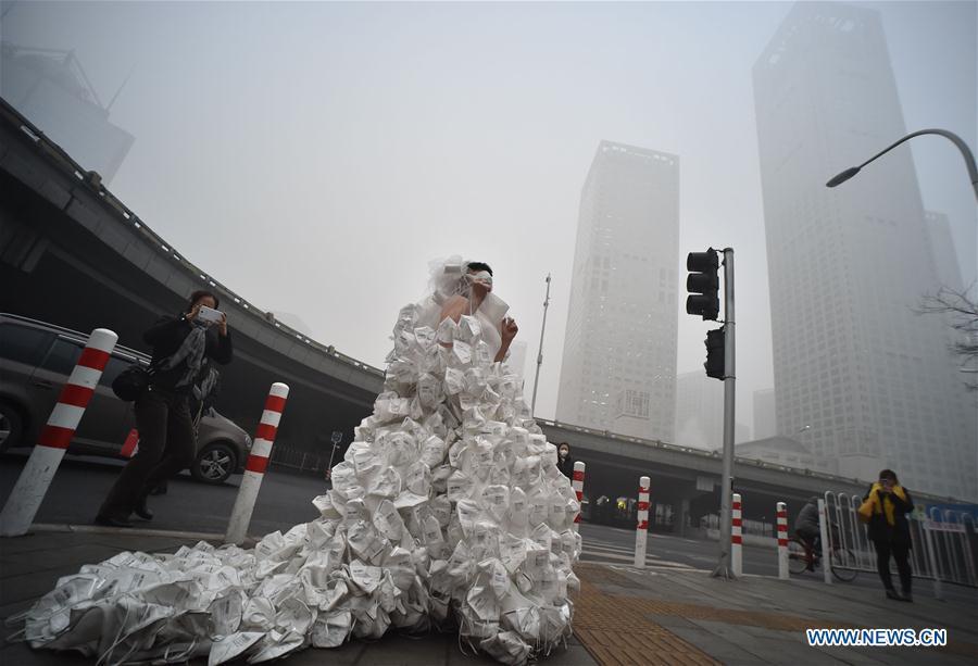 Artist Kong Ning wearing a wedding dress made up with 999 respirators walks on the street to call people