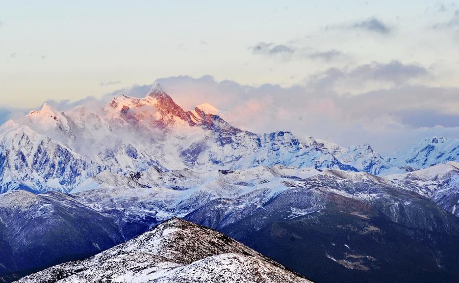 This photo taken on December 20, 2015 from the Sejila Mountain shows the winter scenery of the cloud-shrouded Namjagbarwa peak in Nyingchi, Tibet. The winter air in Nyingchi is fresh, with proper humidity, from the Sejila mountain pass which is at a latitude of 4728m, visitors can watch the stunning sunrise, as well as the mesmerizing view of the sea of clouds or forests. Although currently it is the slack season for tourism, there are still quite a number of visitors coming here to appreciate the unique scenery. Located at the Nyingchi prefecture in Tibet, Namjagbarwa, with an altitude of 7782m, is the fifteenth highest peak in the world. Since its giant triangular top is surrounded by mists and covered with snow all year long, the real appearance of the mountain is rarely seen, so it is nicknamed a "shy" mountain.[Photo/Xinhua]