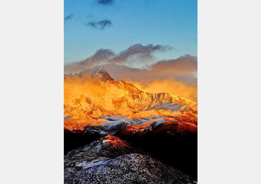 This photo taken on December 20, 2015 from the Sejila Mountain shows the winter scenery of the cloud-shrouded Namjagbarwa peak in Nyingchi, Tibet. The winter air in Nyingchi is fresh, with proper humidity, from the Sejila mountain pass which is at a latitude of 4728m, visitors can watch the stunning sunrise, as well as the mesmerizing view of the sea of clouds or forests. Although currently it is the slack season for tourism, there are still quite a number of visitors coming here to appreciate the unique scenery. Located at the Nyingchi prefecture in Tibet, Namjagbarwa, with an altitude of 7782m, is the fifteenth highest peak in the world. Since its giant triangular top is surrounded by mists and covered with snow all year long, the real appearance of the mountain is rarely seen, so it is nicknamed a "shy" mountain.[Photo/Xinhua]